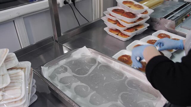 Packaging of ready-made pies in plastic containers at food production