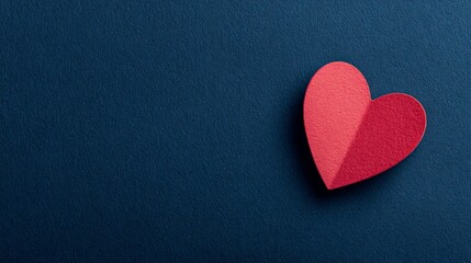 A red paper heart on a dark blue background with copious negative space
