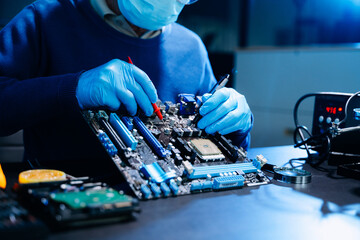 Closeup of expert soldering a green PCB board using precision tools. Ideal for electronics, circuit repair, engineering, tech © Nuttapong punna