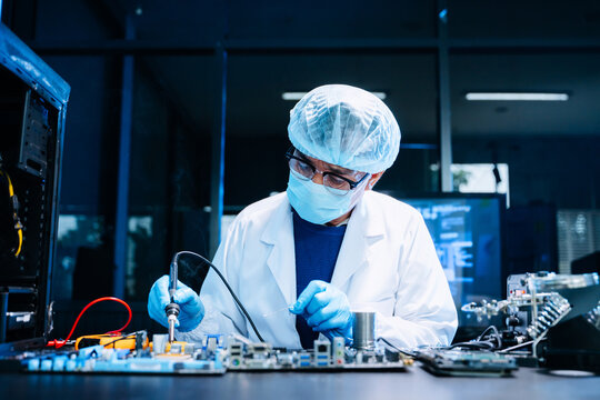 Professional electronics technician repairing computer motherboard in modern lab. Hardware engineering, cybersecurity, data technology, server maintenance