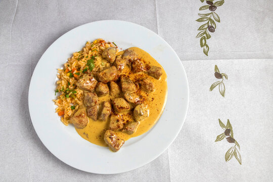 Greek chicken stir fry or Chicken Tigania with sour cream on a plate at a tavern