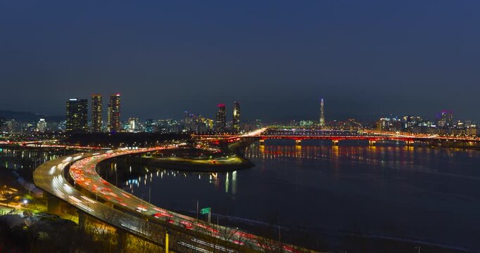 Aerial time-lapse blue hour view of Seoul cityscape featuring Lotte World Tower, illuminated bridges over Han River including Seongsu Bridge, Gangbyeonbuk-ro expressway with heavy traffic light trails