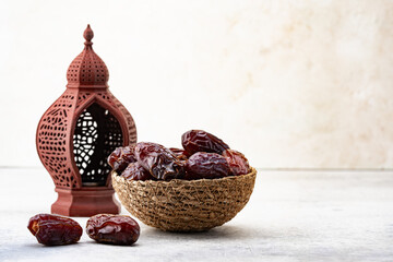 A Ramadan lantern and dates are on a stone table. Ramadan is a holy month for Muslims.