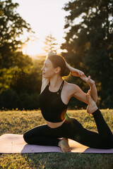 Focused woman performing king pigeon yoga pose outdoors at golden hour, improving flexibility, balance and mindful body awareness in nature.