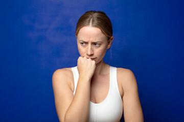 blonde woman feeling serious, thoughtful and concerned, staring sideways with hand pressed against chin