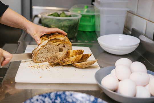 Chef hands slicing sourdough bread on cutting board