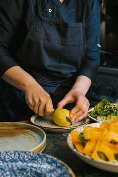 Chef slicing lemon in modern professional kitchen