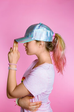 Stylish young woman with dyed hair wearing basecap in front of pink background