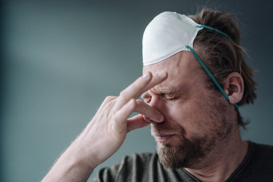 Portrait of man with protective mask holding nose