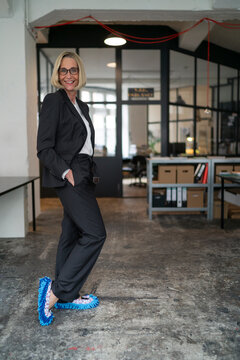Portrait of smiling mature businesswoman wearing cleansing slippers in office
