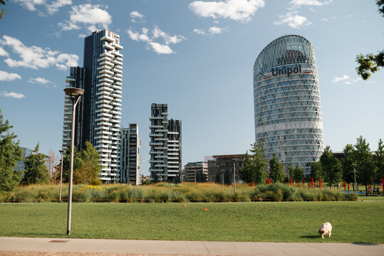 MILAN, ITALY - Juli 16, 2025 Panoramic view of modern Milan skyline with UniCredit Tower and contemporary residential buildings. Urban park foreground, business and lifestyle concept.