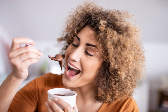 Portrait of happy woman eating chocolate spread at home