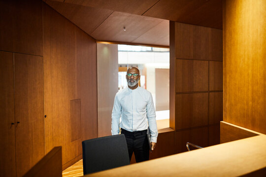 Portrait of mature man with laptop at workspace with wood panelling