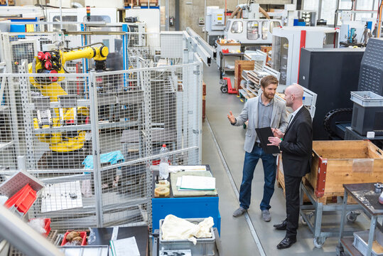 Two businessmen discussing in modern factory