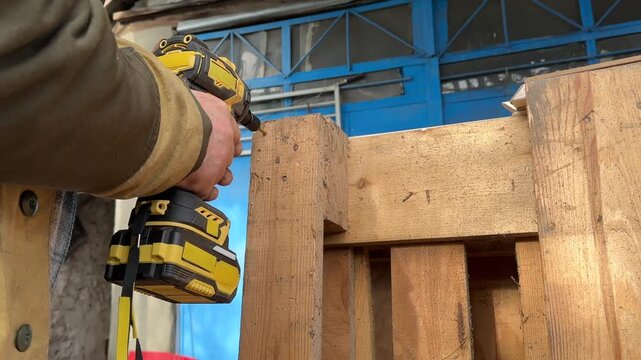 cordless drill drill hole into wooden pallet side angle