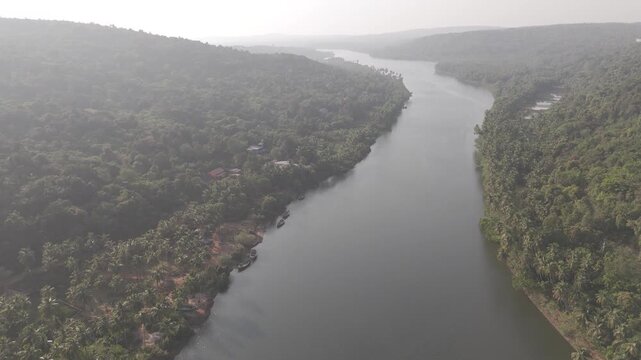 Aerial view of the Tiracol River at the Goa&ndash;Maharashtra border in winter, showing coastal vegetation, mangroves, dry deciduous forest, coconut palms, and native trees along tidal saline waters