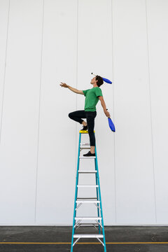 Acrobat standing on ladder, juggling