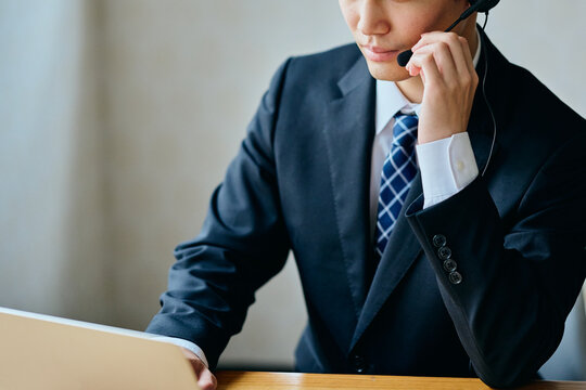 Asian Businessman Working with Headset at Laptop in Office