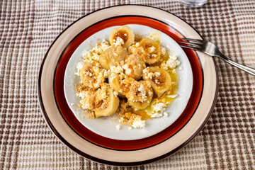 Apricot dumpling with melted butter and breadcrumb on decorative plate with fork.