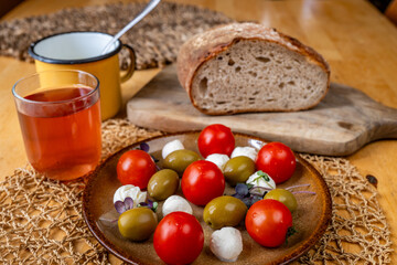 Italian style plate with mini mozarella, cherry tomato and olive, fruit tea, bread.
