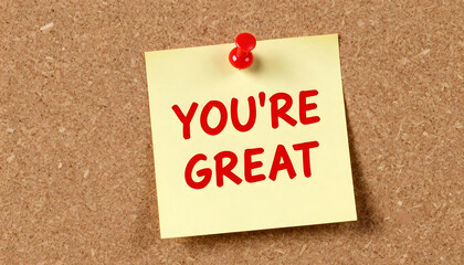 Yellow sticky note with red text saying "You're Great" pinned to a corkboard