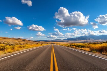 Obraz premium Open Road Under Blue Sky with Changing Clouds and Scenic Landscape Ahead