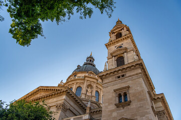 Fototapeta premium Low angle view of St Stephen’s Basilica tower and dome against blue sky in Budapest, historic European architecture, Hungary