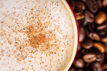 Lots of aromatic coffee beans with coffee in a red cup on a dark background