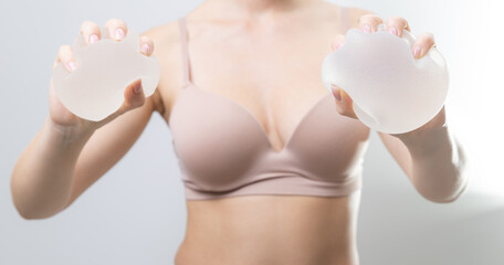 Female adult squeezes silicone breast implants in hands for cosmetic surgery concept, test quality