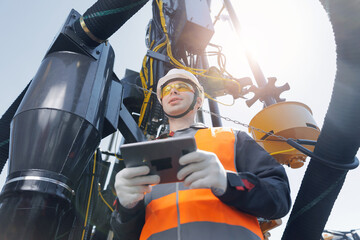 Industry operator young man use computer tablet for control rig platform for drilling