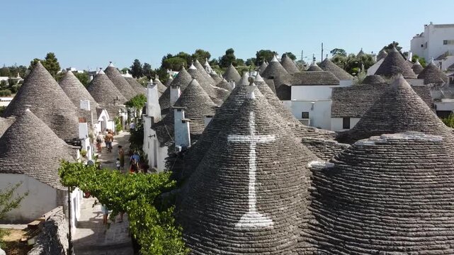 Aerial drone footage of Alberobello, Italy, showcasing the iconic trulli houses with cone-shaped stone roofs. Cinematic view of the historic UNESCO World Heritage town in the Puglia region, captured o