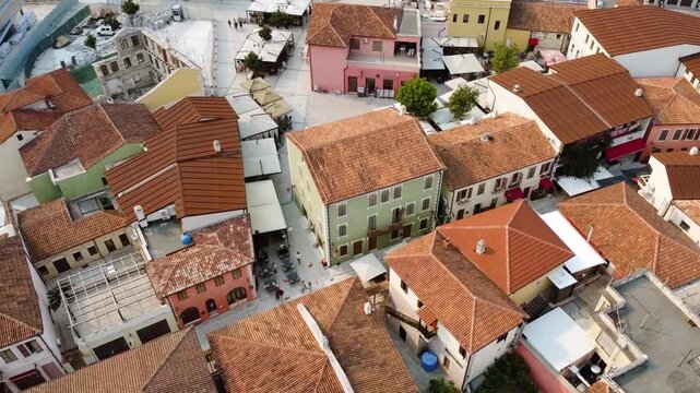 Wide aerial drone footage of Justin Godard Street in Vlor&euml;, Albania on a sunny day, highlighting the surrounding architecture and vibrant city streets.