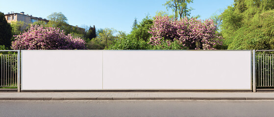 Long white vinyl banner on fence in urban park, Blank hoarding mockup, billboard, signage in city with green blossoming spring trees. Commercial advertisement, public information canvas. Mock up space
