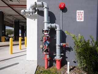 fire hydrant outlet for emergency use with many valve handles on exterior building wall