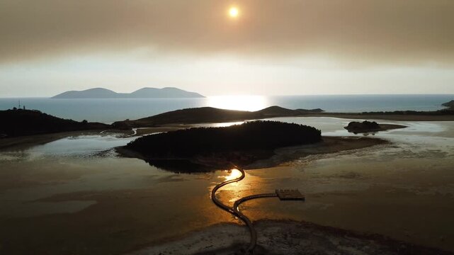 
Aerial drone footage of the Zv&euml;rnec Bridge in Vlor&euml;, Albania at sunset. The video captures warm golden light reflecting on the water, with the historic bridge and surrounding lagoon in view, creating