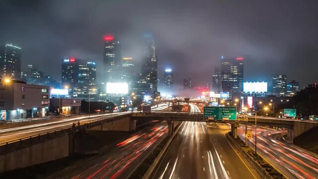 Nighttime cityscape with blurred light trails of traffic on a highway overpass showcasing a vibrant urban scene and modern architectural skyline under a misty sky
