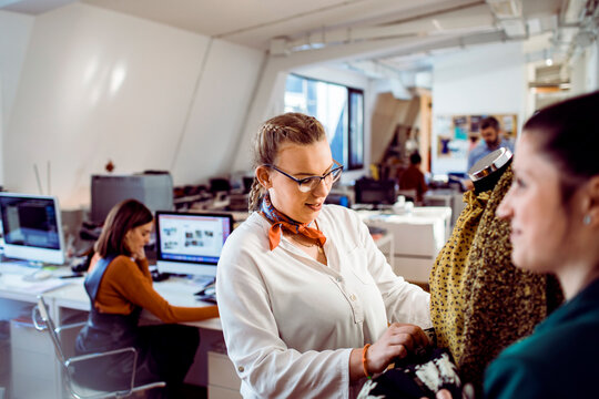 Fashion designers reviewing garments on mannequin in creative office