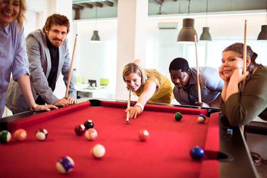 Coworkers playing pool in a modern office break room
