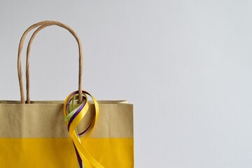 Close-up of a paper bag with handles and brightly colored satin ribbons on a light background