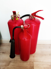 Red fire extinguishers standing on a floor against a white wall for safety compliance