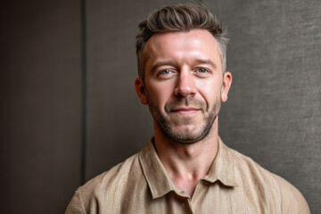 Obraz premium Portrait of Caucasian middle aged man looking into camera with slight smile, short hair and trimmed beard, standing against plain background, showing confident expression