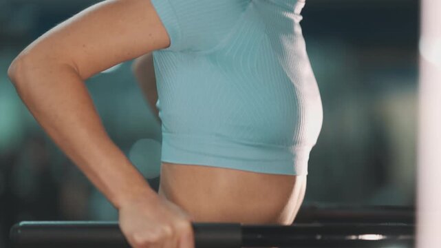 Athletic woman performing triceps dips exercise at gym