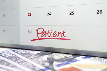 Calendar with the word Patient handwritten in red ink over US hundred dollar bills. Concept for long-term investing, delayed gratification, and steady wealth accumulation.