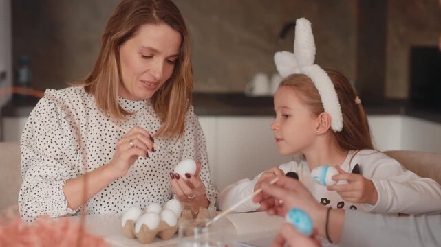 Happy Family Decorating Easter Eggs Together with Brushes and Paint