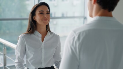 Fototapeta premium Two Caucasian business colleagues talking in company hall businesswoman talk serious with businessman in office corridor coworkers partners communicating discuss project man with woman communicate