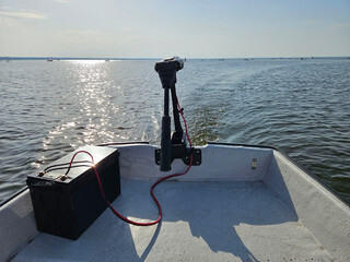 Boat with a battery and a electric motor on it. The battery is black and lake sunny