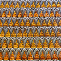 Fototapeta premium Golden Buddha statues in niches at Kek Lok Si Temple, Penang, Malaysia. Rows of sculptures in meditative poses.