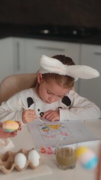 Little Girl with Bunny Ears Enjoys Coloring an Easter Bunny for the Holiday