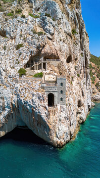 The iconic facade of Porto Flavia ore loading terminal carved into the cliffs above the turquoise waters of the Mediterranean Sea in Masua, Sardinia