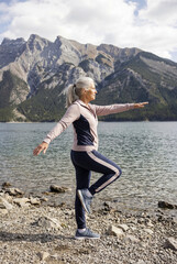 An elderly woman doing stretching exercises outdoors. An active, healthy lifestyle.